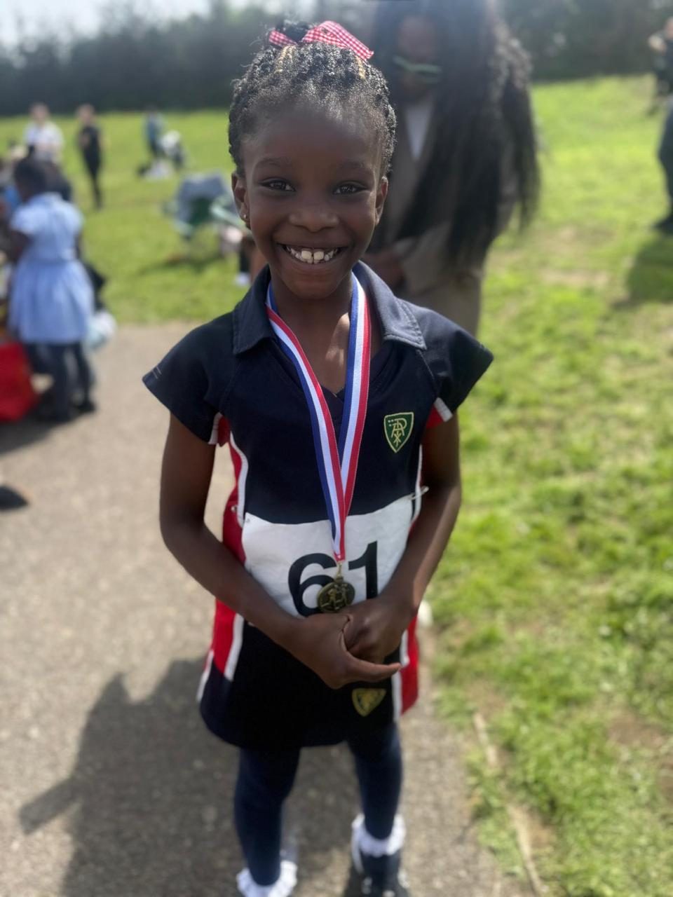 A pupil beams with pride, holding up her sports day medal.