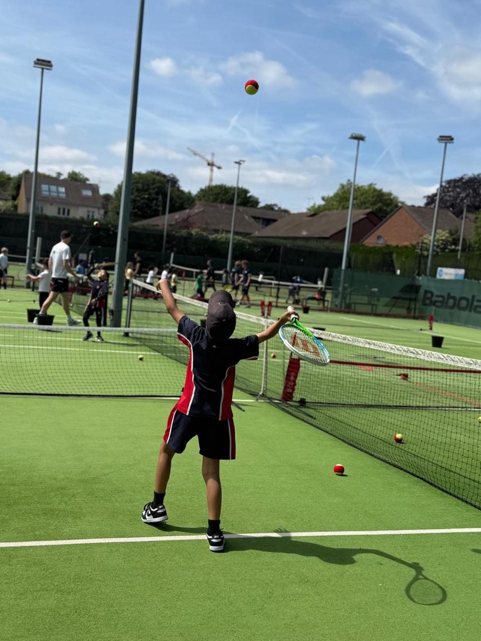 A pupil serves the ball on the tennis courts.