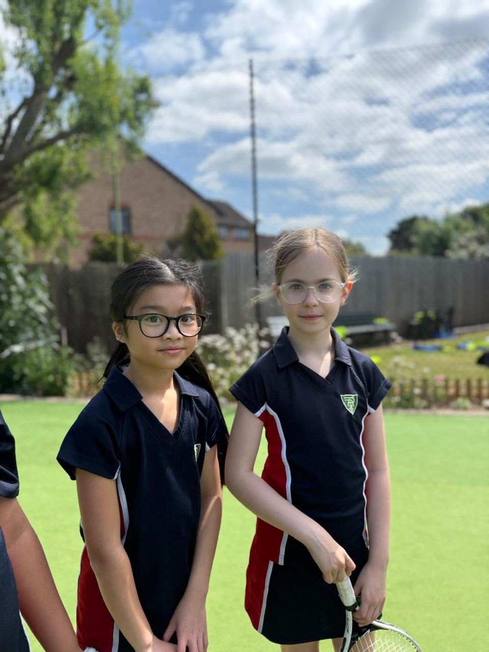 Two pupils practise together on the tennis court.