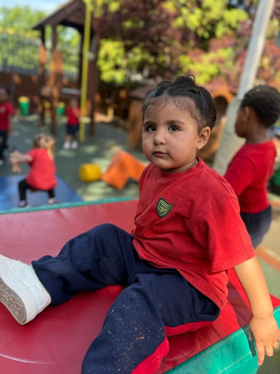 A toddler plays on a red mat in the Early Years playground.