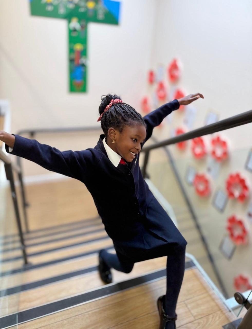 A child dances joyfully on the steps beside a bed of poppies.