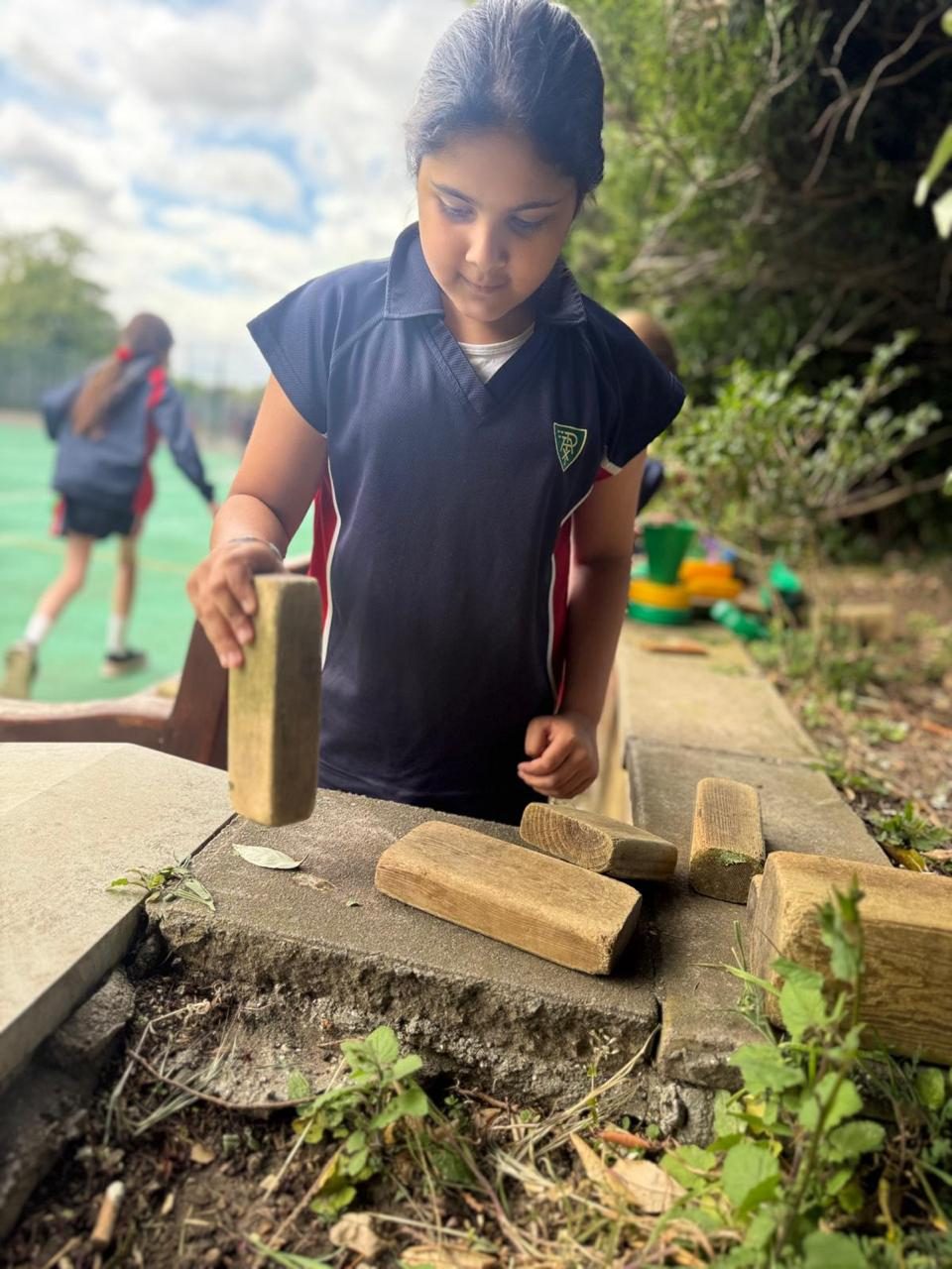 A child builds with wooden blocks during outdoor play.