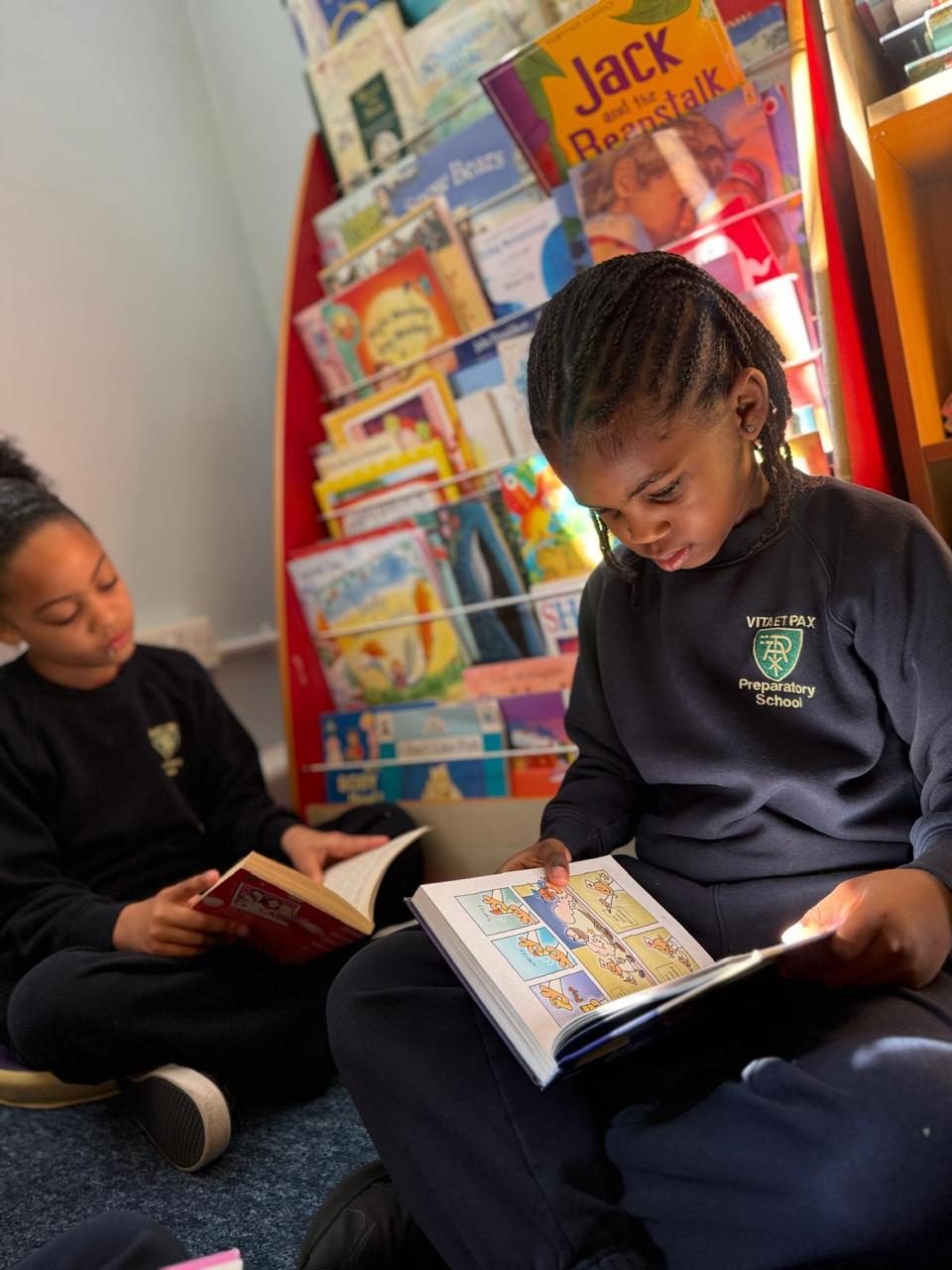 Two children choose a book together in the school library.