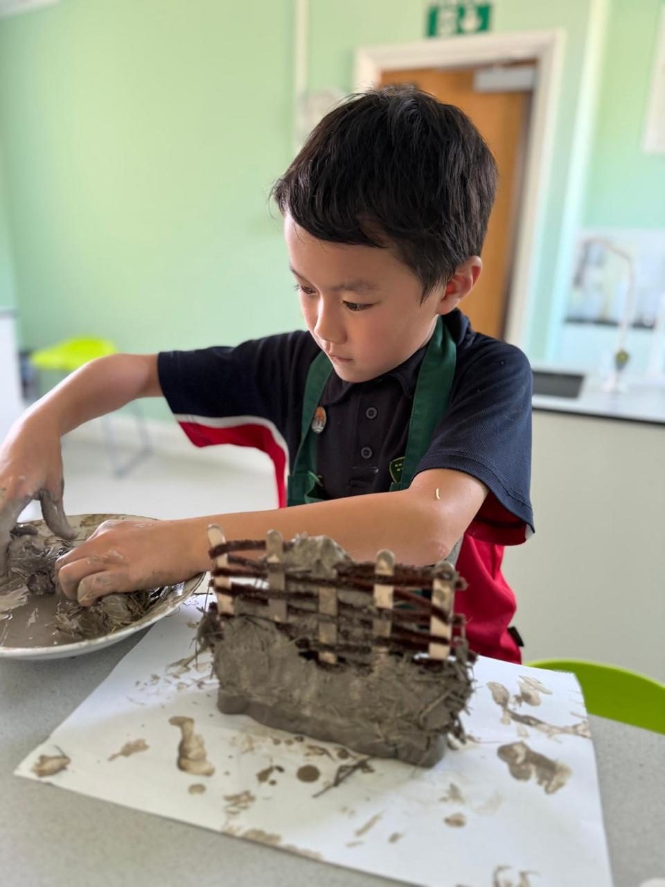 A pupil shapes a clay artwork during an outdoor art session.