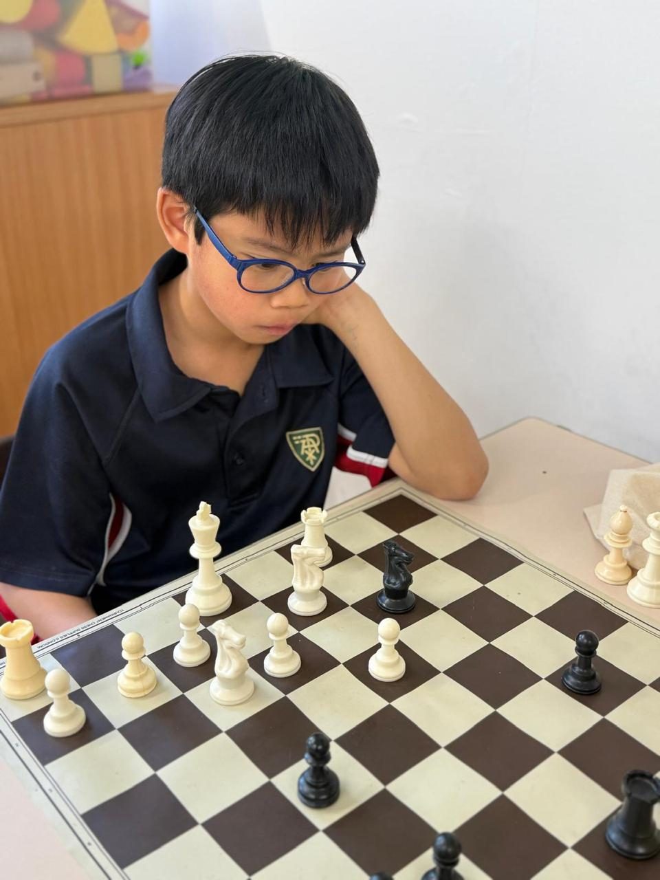 A pupil studies the board intently during a game of chess.
