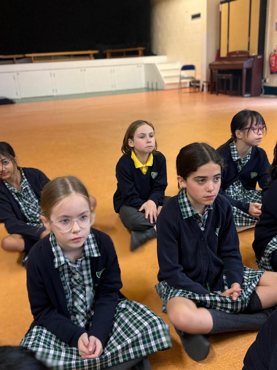 Pupils sit together in the school hall.