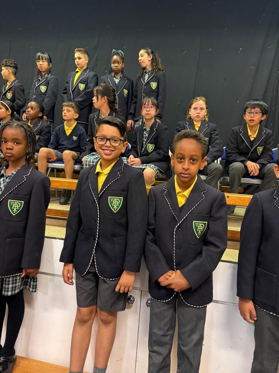 A group of pupils in school blazers on stage.
