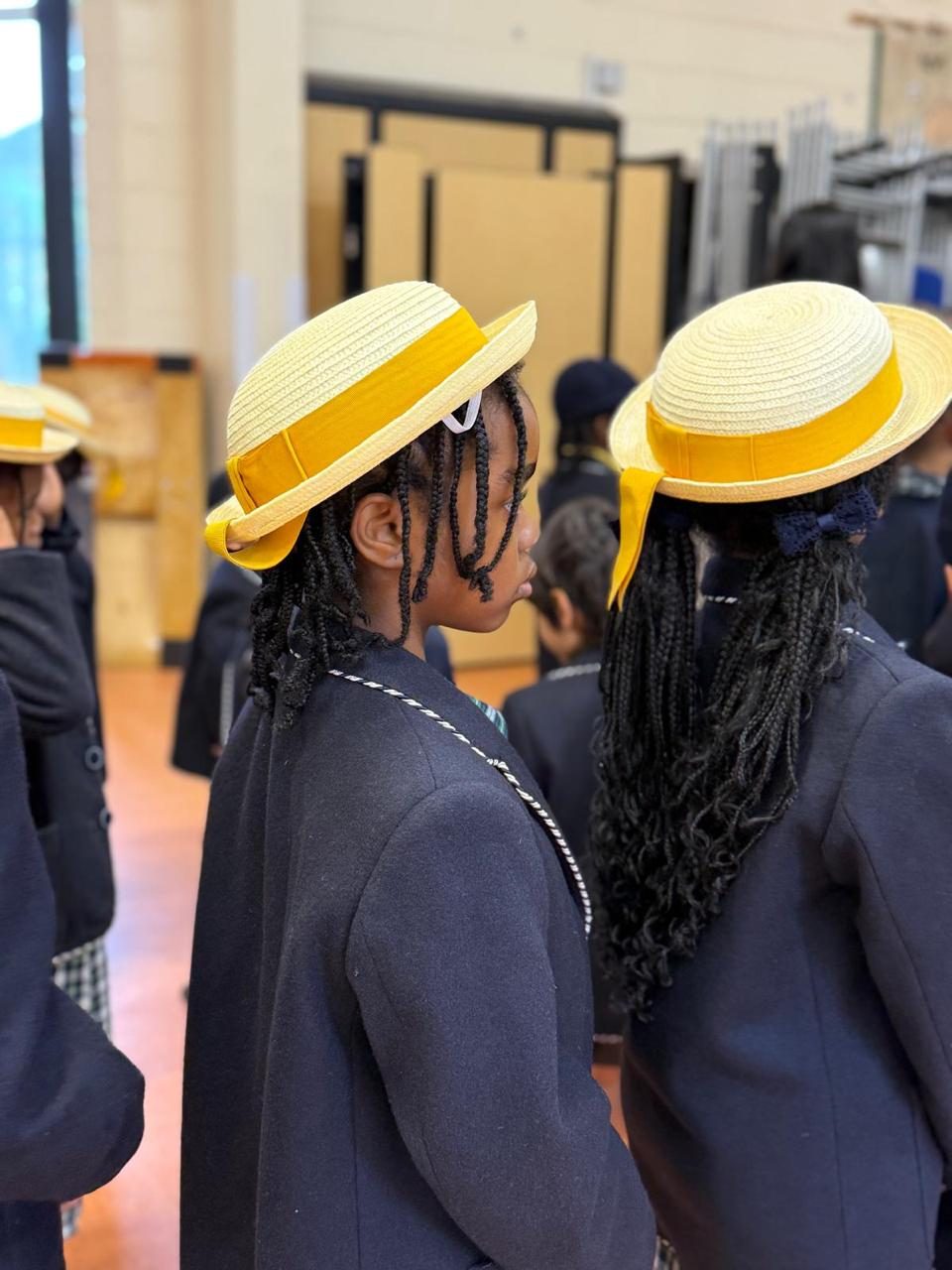 Two pupils wearing summer straw boaters, part of the school uniform.