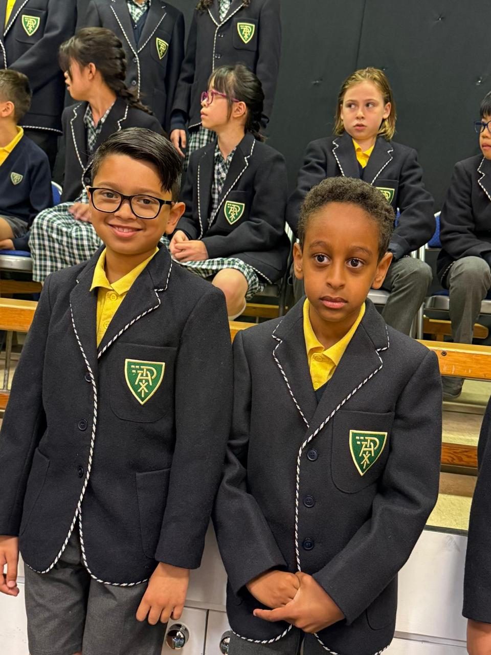Two pupils in school blazers share a smile.