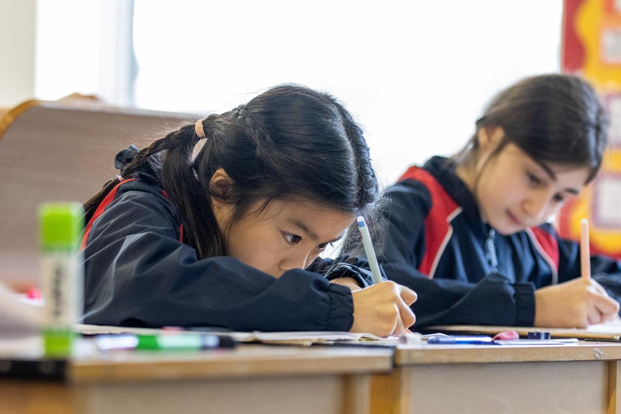 Pupils writing with focus in a Vita et Pax prep school lesson, North London