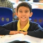 child sat with a book on the table