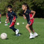 2 students playing football on a field