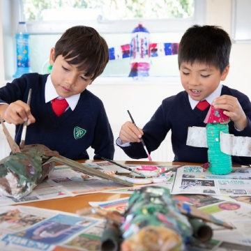 students painting glue onto pieces of newspaper