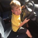 child at the steering wheel, not driving a car