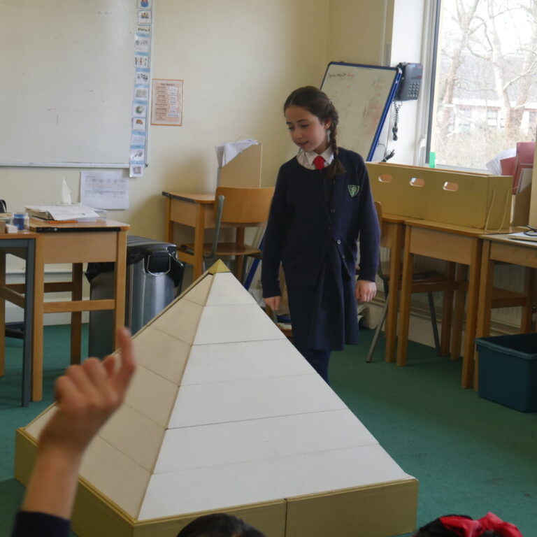 student walking near a small pyramid model